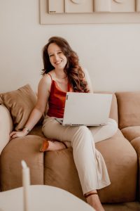 Eelke lachend op de bank met haar laptop tijdens de brandingshoot